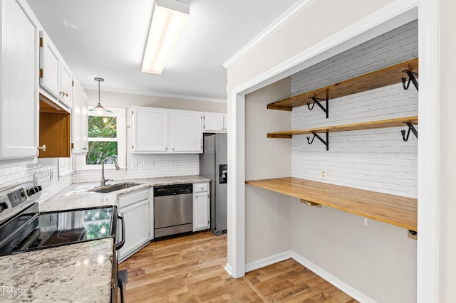 kitchen with white cabinets, appliances with stainless steel finishes, a sink, light wood-style flooring, and tasteful backsplash