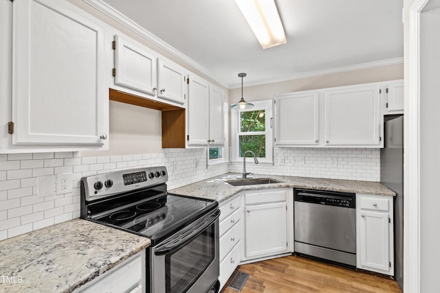 kitchen with a sink, white cabinets, ornamental molding, and stainless steel appliances