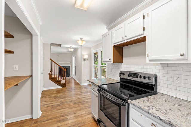 kitchen featuring backsplash, baseboards, light wood-style floors, and stainless steel range with electric stovetop