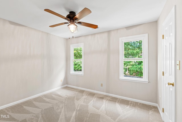 carpeted empty room with baseboards, a ceiling fan, and plenty of natural light