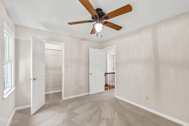 unfurnished bedroom featuring baseboards, ceiling fan, a walk in closet, and carpet