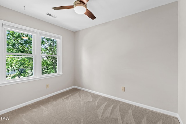 carpeted spare room with baseboards, ceiling fan, and visible vents