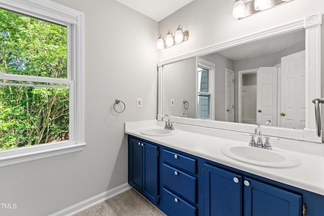 bathroom with baseboards, a sink, marble finish floor, and double vanity