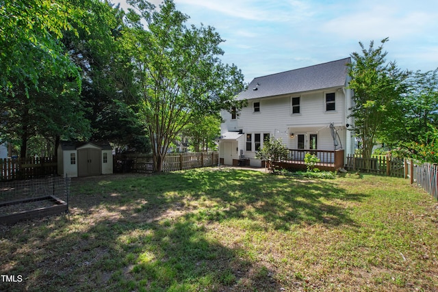 rear view of property featuring a lawn, a deck, an outbuilding, a shed, and a fenced backyard