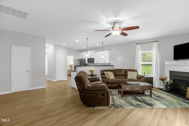 1305 Montreux Ct, Mebane, NC 27302 - living room featuring light wood finished floors, a ceiling fan, visible vents, and baseboards