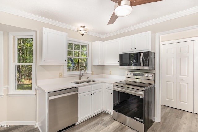 kitchen with plenty of natural light, a sink, light countertops, white cabinets, and stainless steel appliances