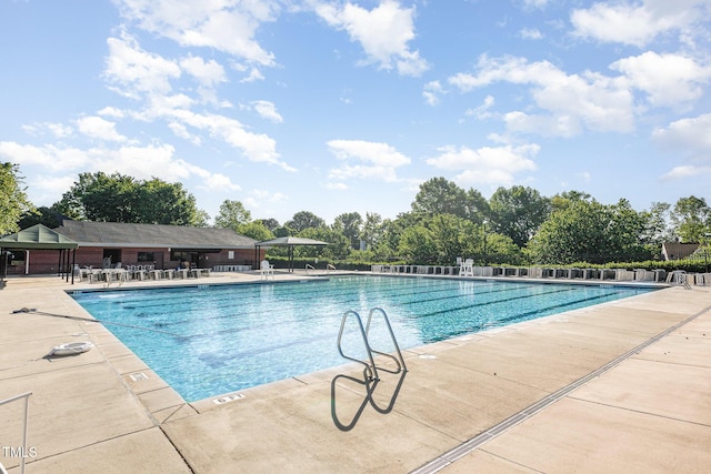 community pool with a patio area and fence