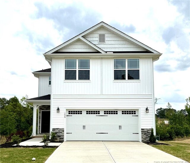 view of front facade featuring stone siding, driveway, and an attached garage
