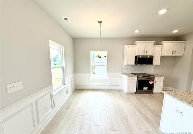 kitchen featuring light stone counters, wainscoting, appliances with stainless steel finishes, white cabinets, and light wood finished floors