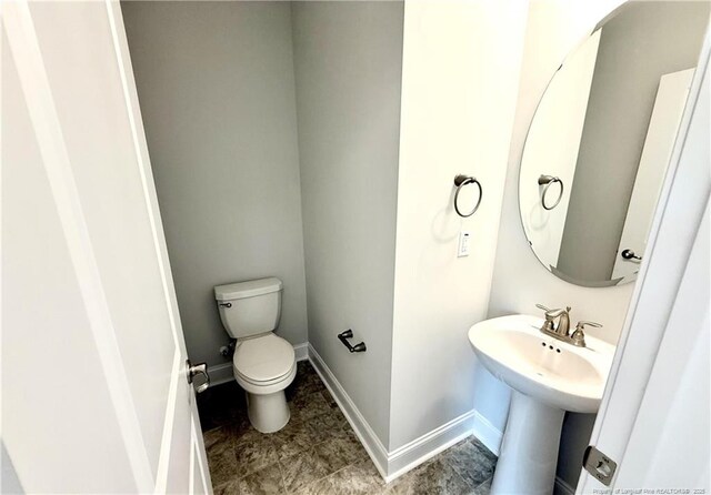 bathroom with toilet and baseboards