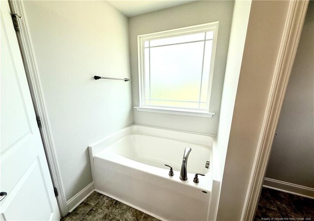 bathroom with baseboards and a bath