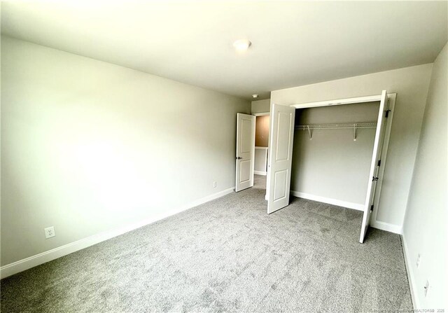 unfurnished bedroom with a closet, carpet floors, and baseboards