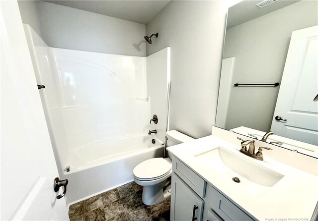 bathroom featuring toilet, vanity, shower / bath combination, and stone finish flooring
