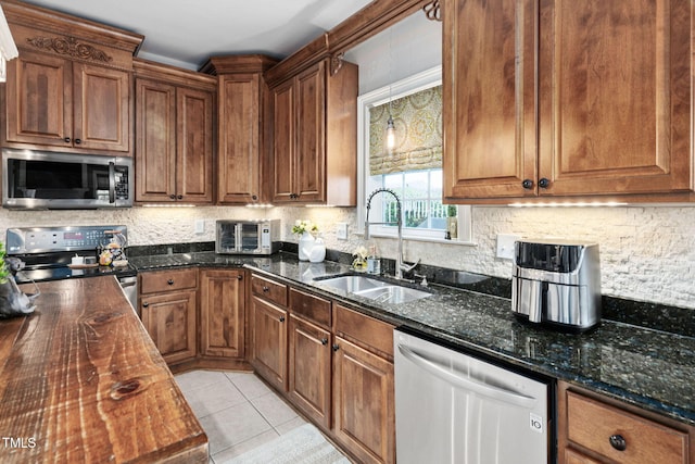 48 Falling Oak Ct, Clayton, NC 27520 - kitchen featuring stainless steel appliances, a sink, backsplash, dark stone counters, and light tile patterned flooring