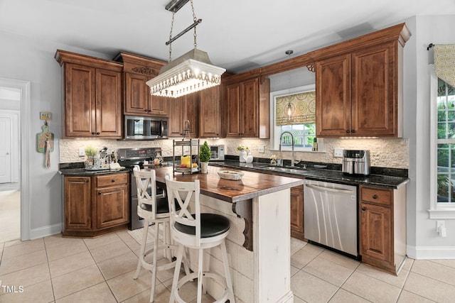 48 Falling Oak Ct, Clayton, NC 27520 - kitchen featuring stainless steel appliances, a sink, light tile patterned flooring, tasteful backsplash, and a kitchen island