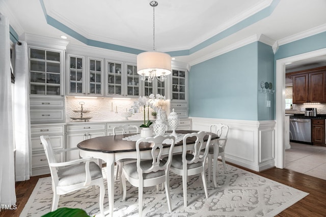 48 Falling Oak Ct, Clayton, NC 27520 - dining area featuring light wood-type flooring, a chandelier, a wainscoted wall, and ornamental molding