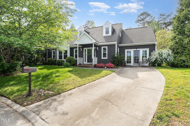 new england style home featuring driveway, a shingled roof, and a front lawn