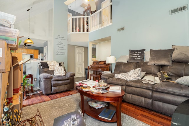 living area featuring wood finished floors, visible vents, and a high ceiling