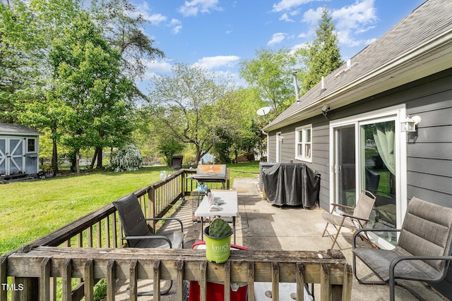 wooden deck with an outbuilding, a lawn, a shed, and a patio