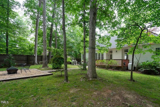 view of yard featuring a fire pit, fence, and a wooden deck
