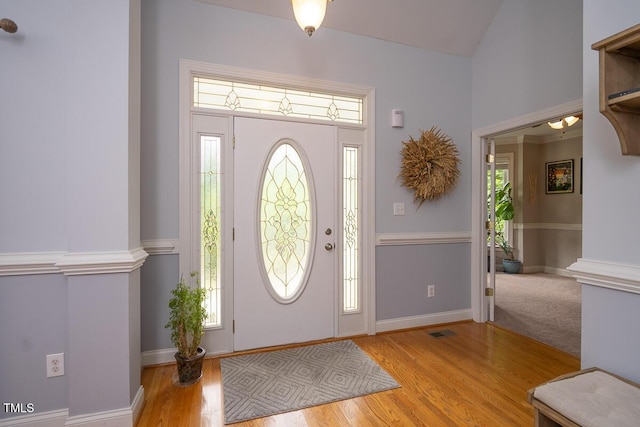 foyer featuring baseboards, visible vents, wood finished floors, and a wealth of natural light
