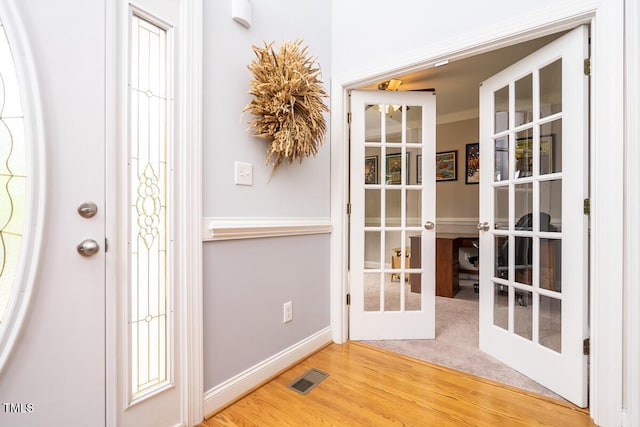 entryway with visible vents, french doors, baseboards, and light wood-style floors
