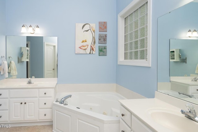 bathroom with a tub with jets, two vanities, and a sink
