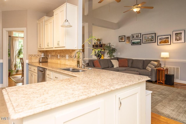 kitchen featuring stainless steel dishwasher, a sink, visible vents, open floor plan, and a ceiling fan