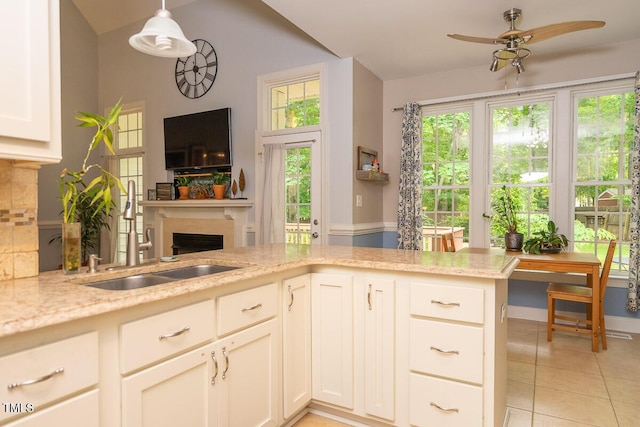 kitchen featuring a healthy amount of sunlight, a fireplace, a sink, a ceiling fan, and light tile patterned flooring
