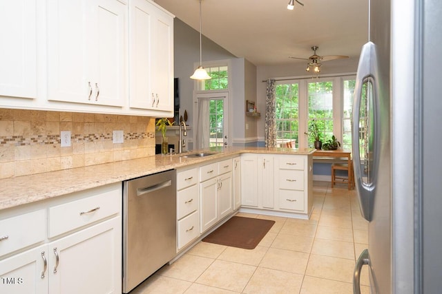 kitchen with a sink, stainless steel appliances, decorative backsplash, light tile patterned floors, and a peninsula