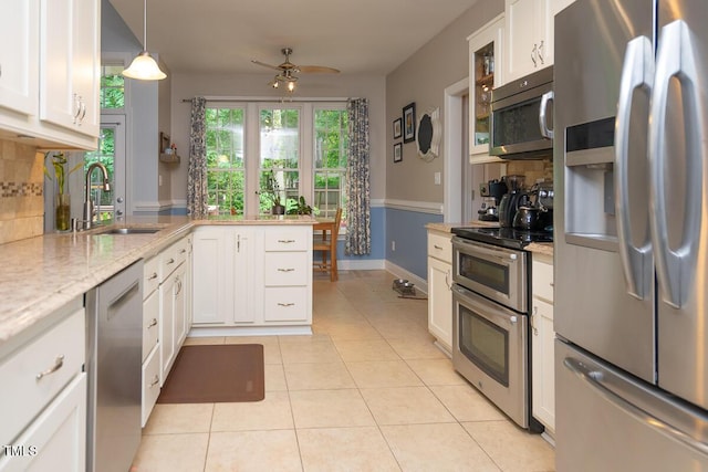 kitchen with appliances with stainless steel finishes, white cabinets, backsplash, a sink, and a peninsula