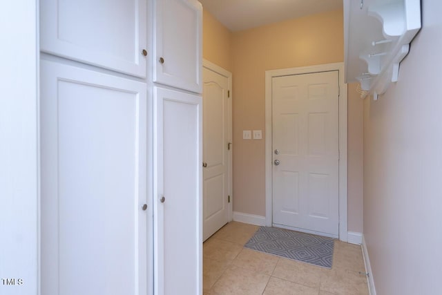 doorway to outside featuring light tile patterned flooring and baseboards