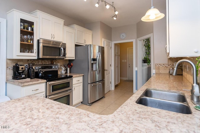 kitchen with light tile patterned floors, white cabinetry, a sink, appliances with stainless steel finishes, and light countertops