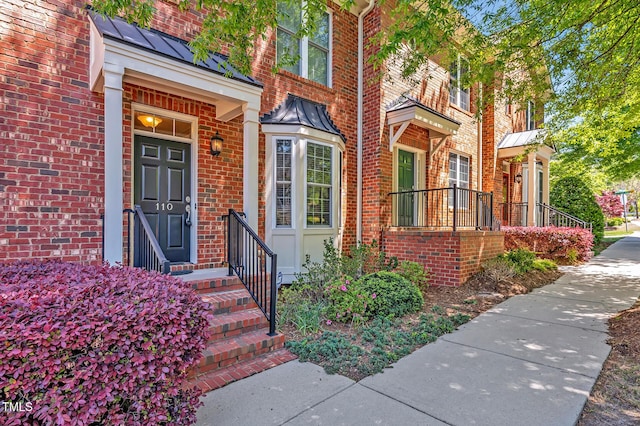 doorway to property with a standing seam roof, metal roof, and brick siding