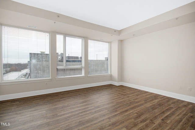 empty room with baseboards and dark wood-type flooring