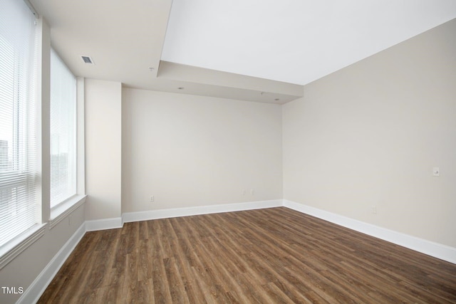 empty room with baseboards, visible vents, and wood finished floors