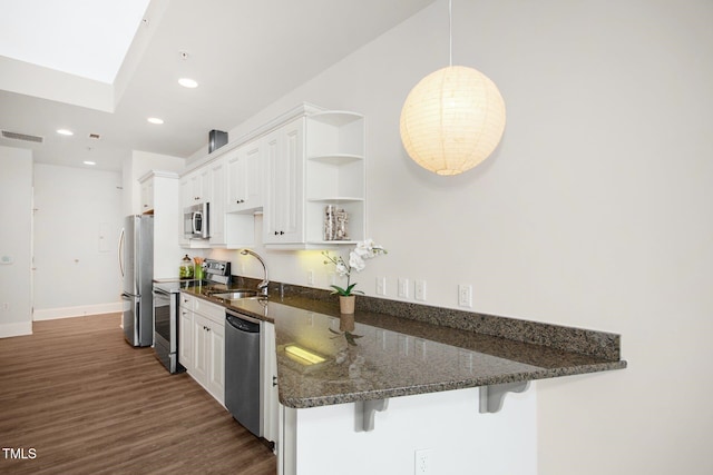 kitchen with white cabinets, open shelves, appliances with stainless steel finishes, a breakfast bar, and visible vents