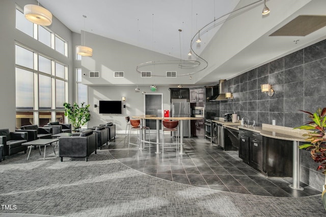 kitchen with a breakfast bar, tile walls, wall chimney range hood, light countertops, and stainless steel appliances