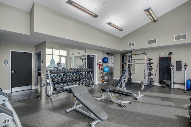 gym featuring baseboards, visible vents, and high vaulted ceiling