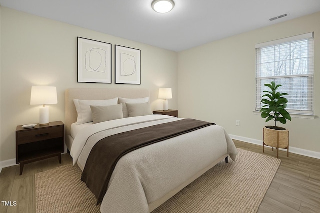 bedroom with light wood-type flooring, baseboards, and visible vents
