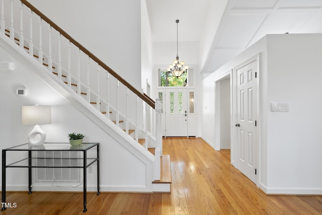 entryway with stairs, baseboards, a chandelier, and light wood-style flooring