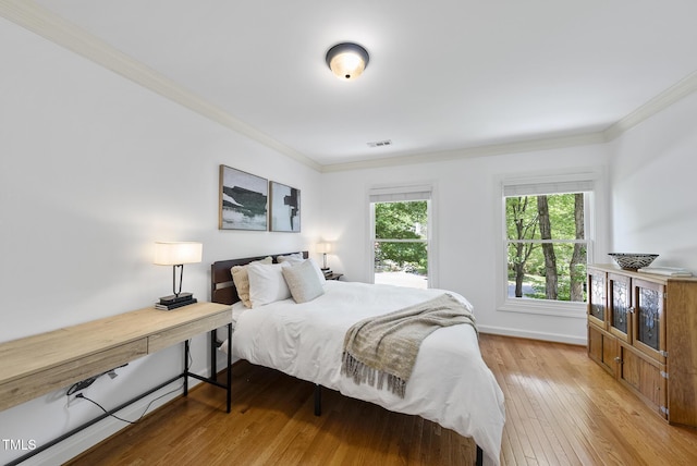 bedroom with crown molding, baseboards, visible vents, and hardwood / wood-style floors