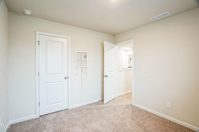 unfurnished bedroom featuring baseboards, visible vents, and carpet