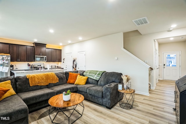 living room with light wood finished floors, baseboards, visible vents, recessed lighting, and stairway