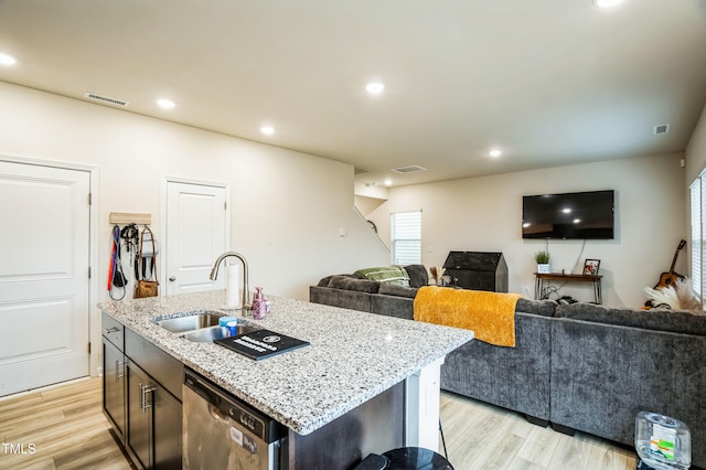 kitchen featuring open floor plan, dishwasher, a sink, and light wood-style floors