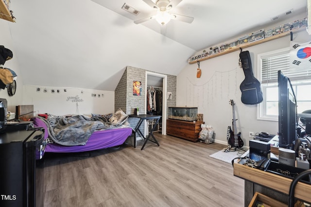 bedroom with a closet, light wood finished floors, vaulted ceiling, and visible vents