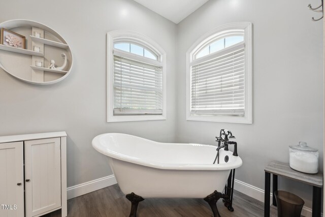 bathroom featuring a freestanding tub, baseboards, and wood finished floors