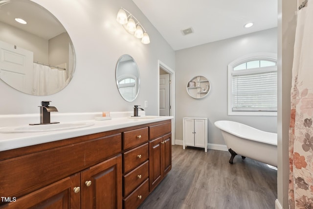 bathroom featuring visible vents, a sink, wood finished floors, and double vanity