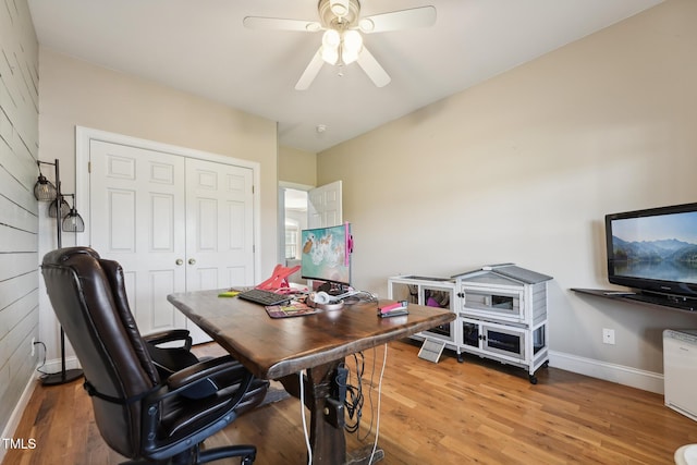office space with baseboards, a ceiling fan, and light wood-style flooring