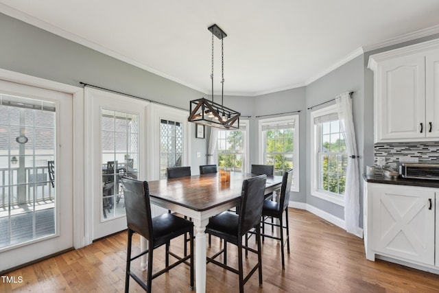 dining area with an inviting chandelier, baseboards, ornamental molding, and light wood finished floors